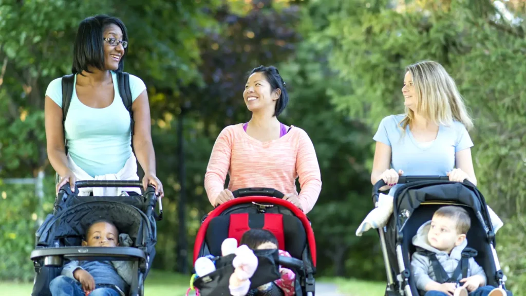 Three moms talking and pushing strollers