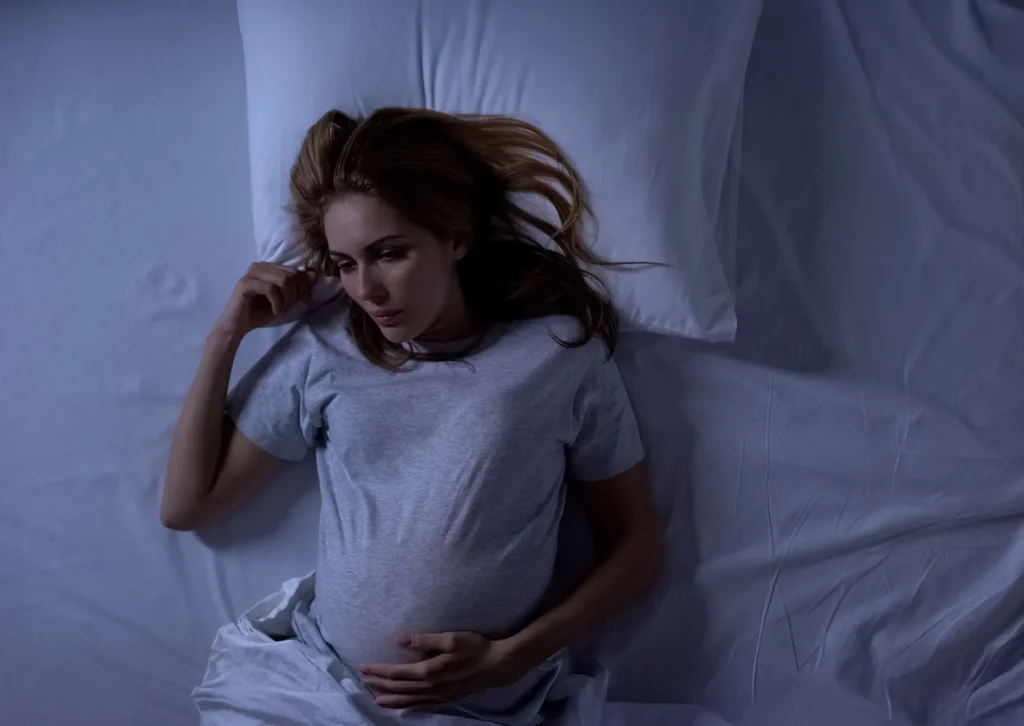 A pregnant woman awake in bed at night