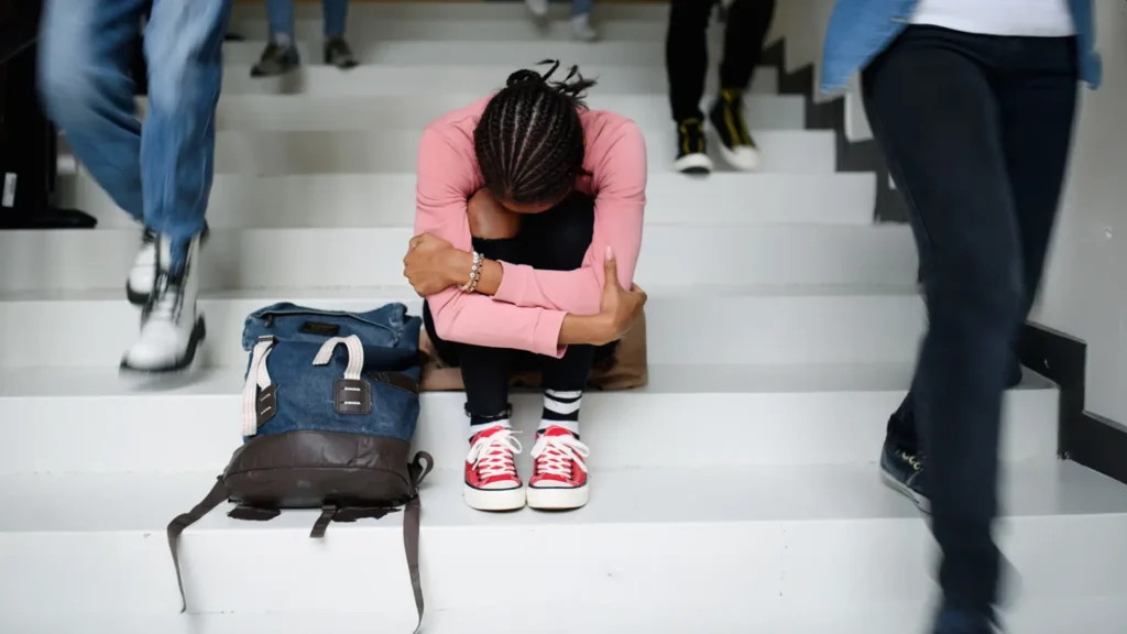 A young woman sitting on steps with her head down